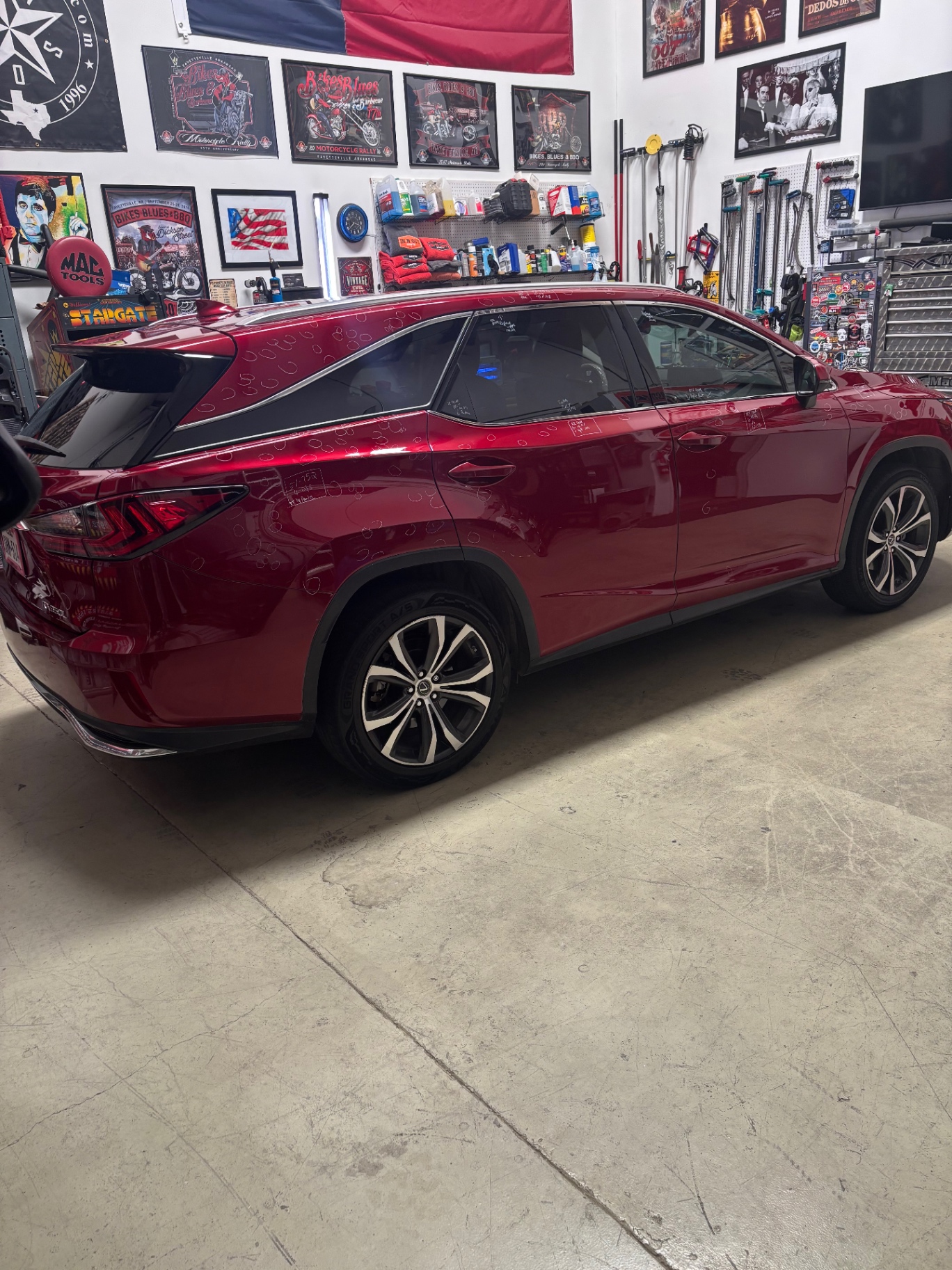 Red Lexus RX with hail damage marked for repair in the shop