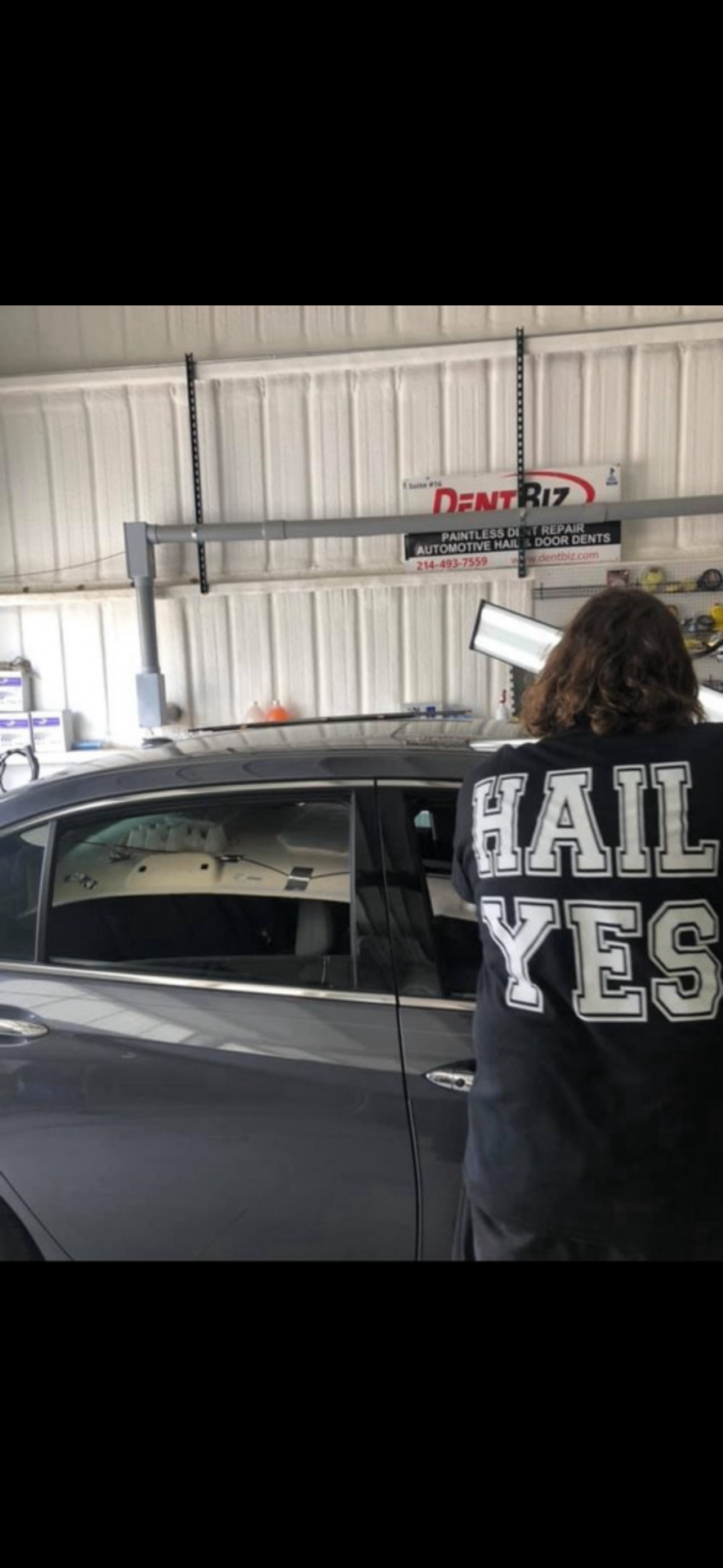 Technician performing paintless dent repair on a sedan